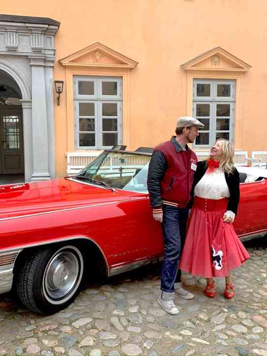 Christian Wöhlk und Conny Landsberger vor ihrem roten Cadillac Cabriolet im Schlosshof Eutin.