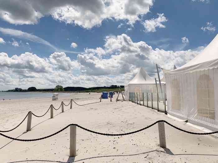 Weißer Sandstrand, blauer Himmel mit Schäfchenwolken die türkies farbene Ostsee, ein weißes Pagodenzelt - die perfekte Hochzeitskulisse.