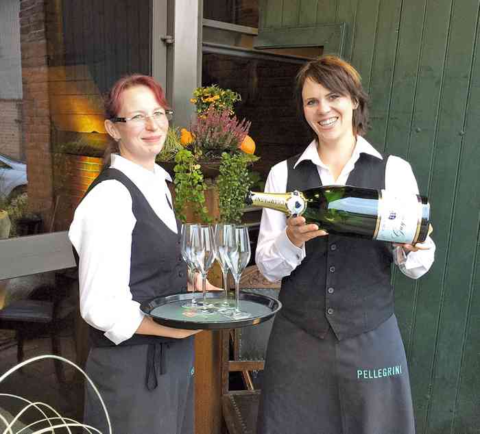 Zwei Servicemitarbeiterinnen schenken Champagner ein in der Hochzeitslocation Pellegrini Margarethenhoff .