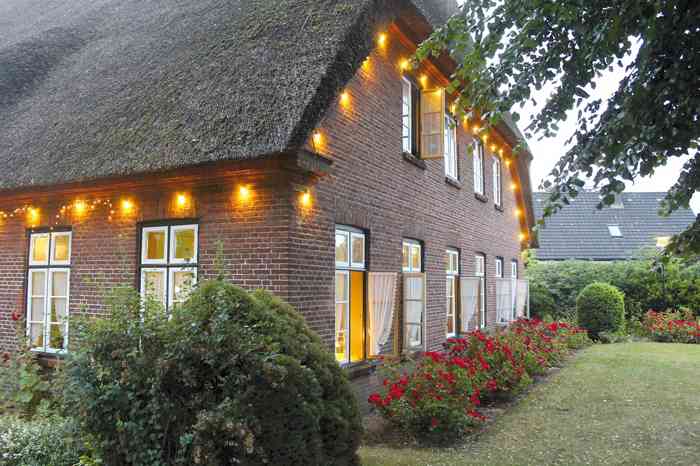 Reetdachhaus mit Lampions und Garten der Hochzeitslocation Pellegrini Margarethenhoff.