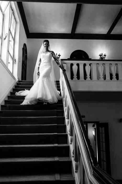 Die Braut schreitet im Hochzeitskleid die Treppe des Hotel Louis C. Jacob hinunter.