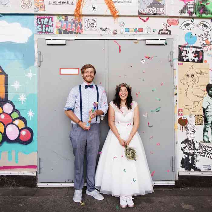 Hochzeitspaar steht vor einem Graffity, fotografiert von Helen Fischer.