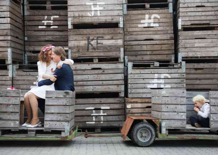 Hochzeitspaar sitzt auf enem Anhänger mit Obstkisten, fotografiert von Helen Fischer.